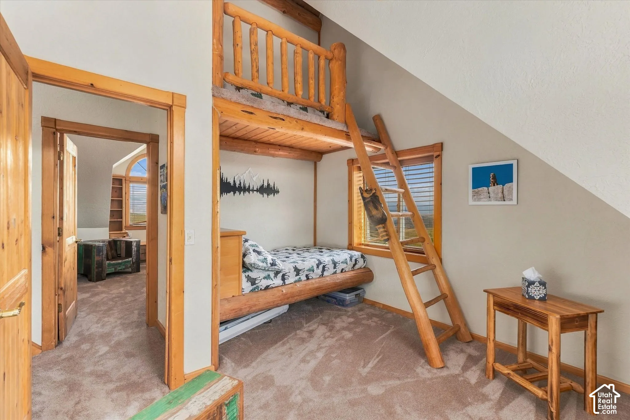 Wood-finish bunk bed with a ladder and railing, set against an angled ceiling