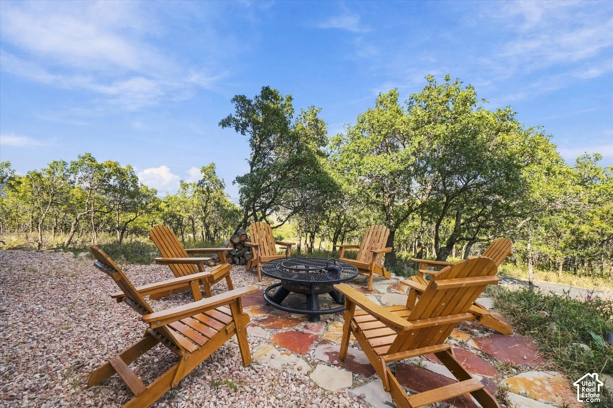 Outdoor entertainment area featuring a circular fire pit, flagstone patio, and surrounding gravel landscaping