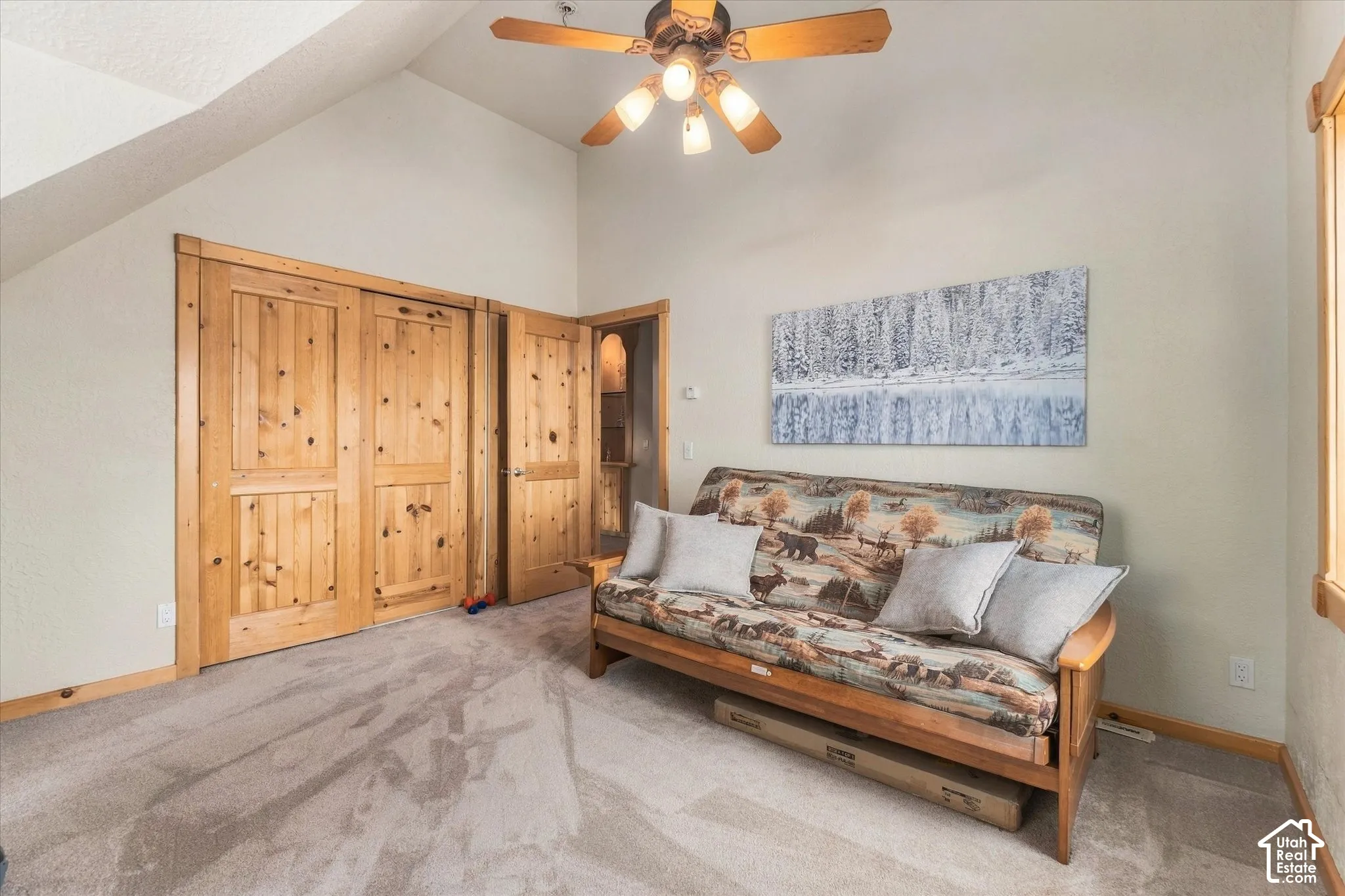 Vaulted ceiling with a ceiling fan, carpet flooring, natural wood doors, and natural wood window trim