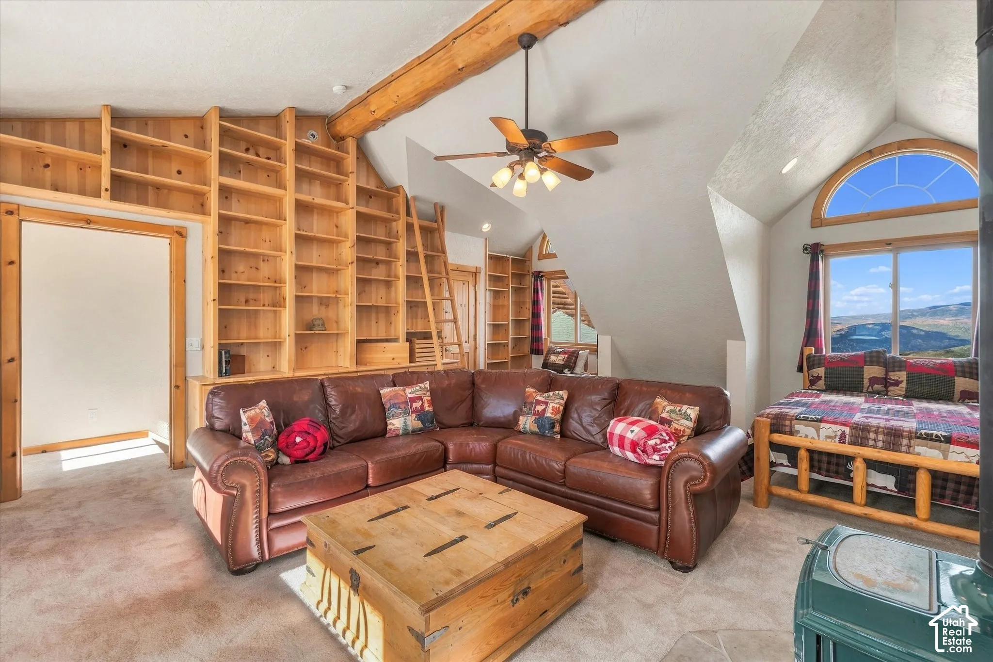 Built-in wood shelving with a rolling ladder, exposed wood beam ceiling, and a ceiling fan