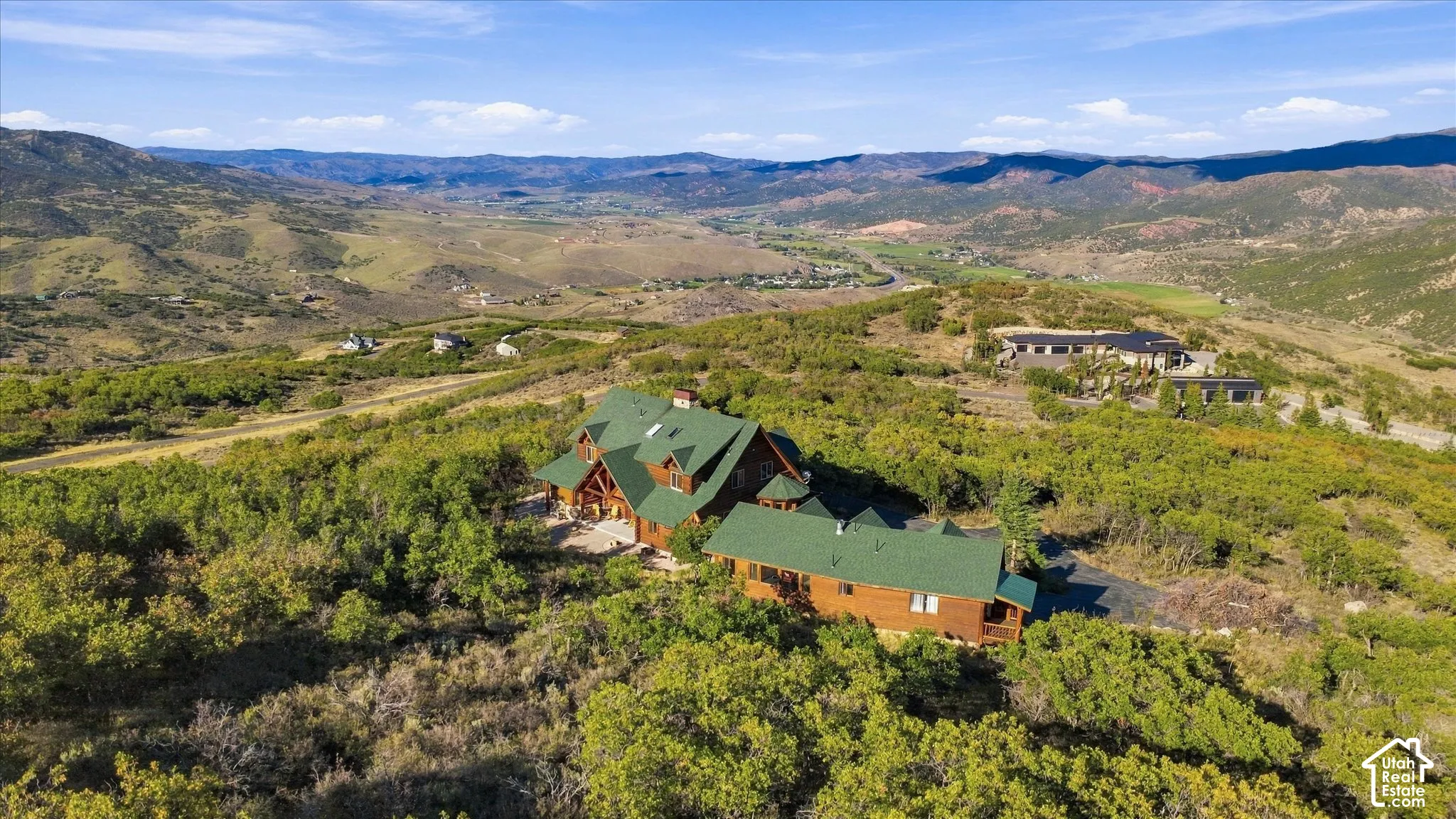 Expansive mountain landscape with a large residence featuring a green roof, wood siding, and multiple gables