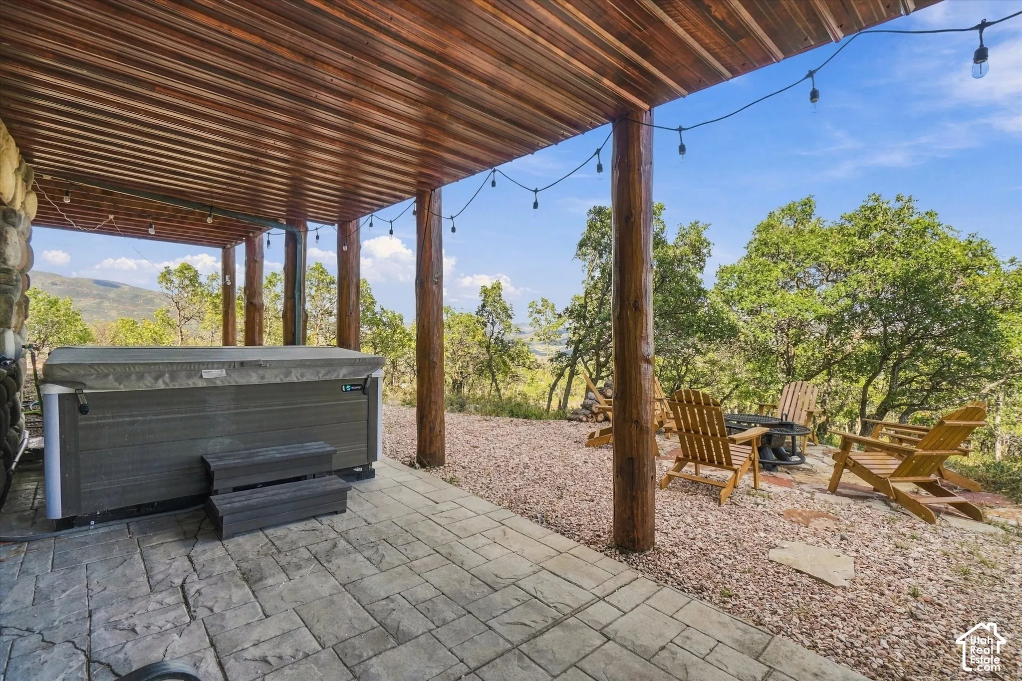 Covered outdoor space featuring a hot tub, stamped concrete patio, and string lighting