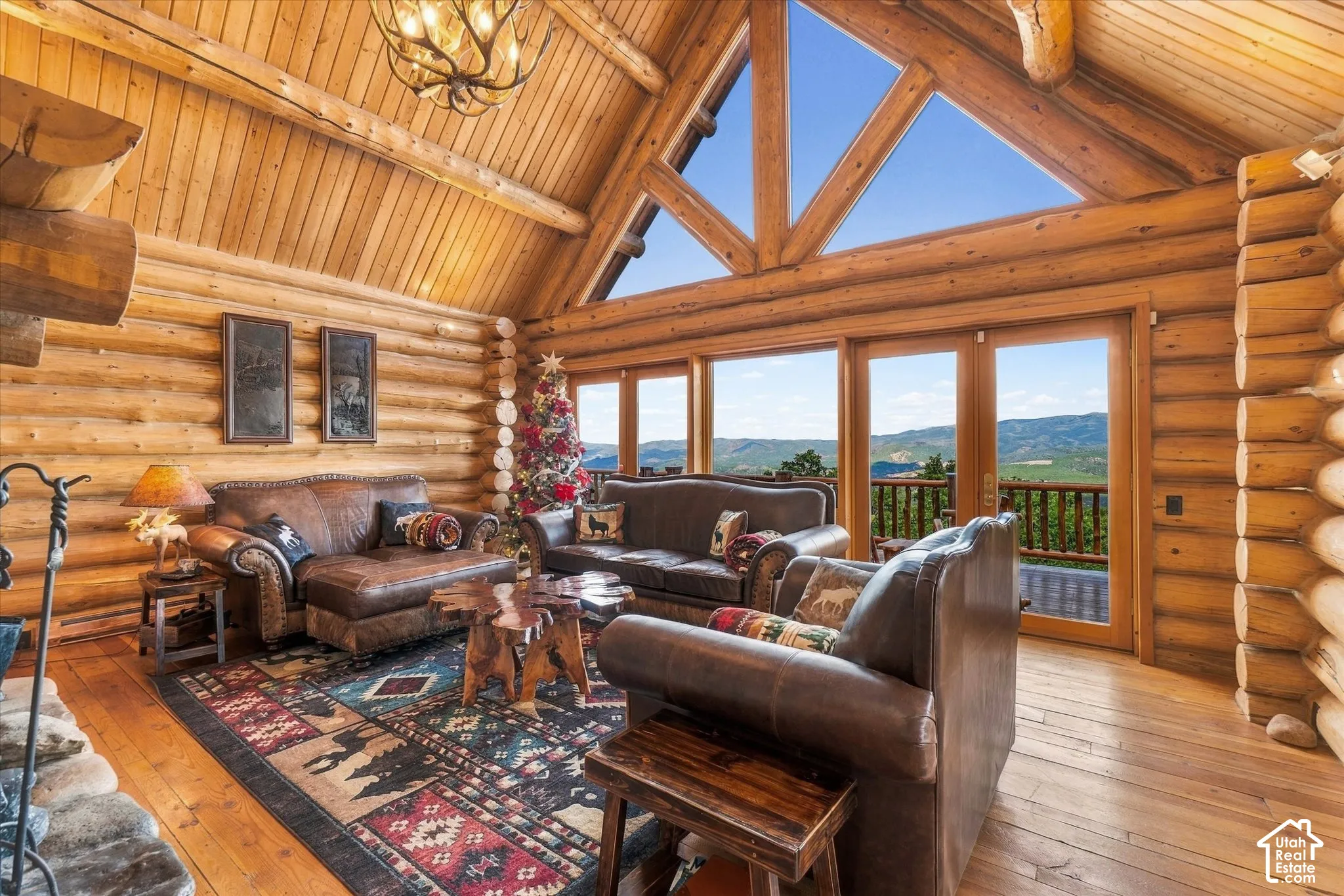 Vaulted ceiling with exposed beams, wood-plank walls and ceiling, large windows, and a built-in fireplace