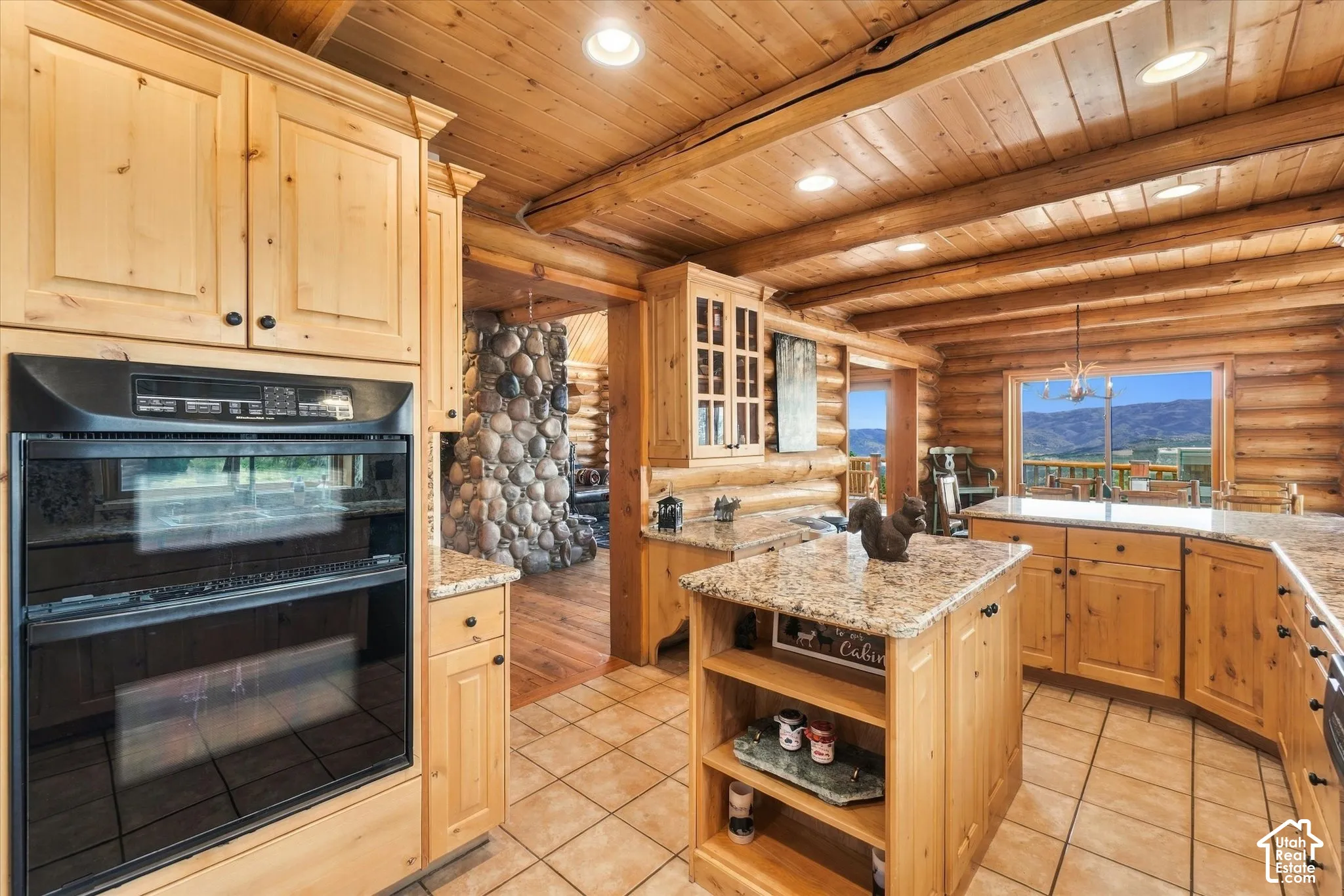 Kitchen with light wood cabinetry, stone countertops, and a built-in double oven