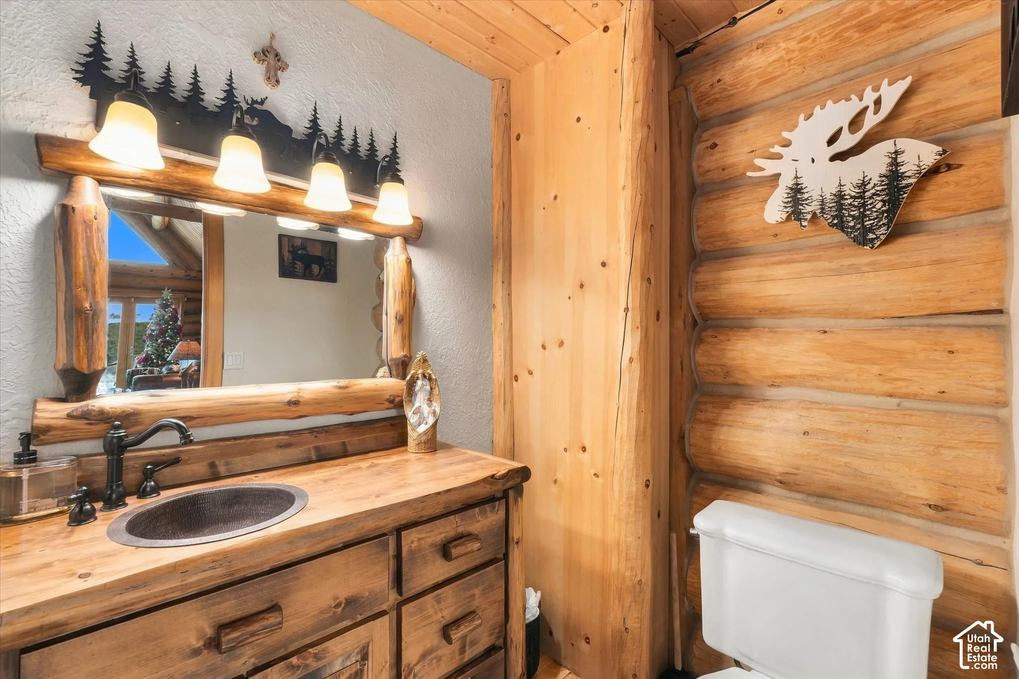 Wood-finish vanity with an oval vessel sink, bronze-finish faucet, and coordinating wood-frame mirror
