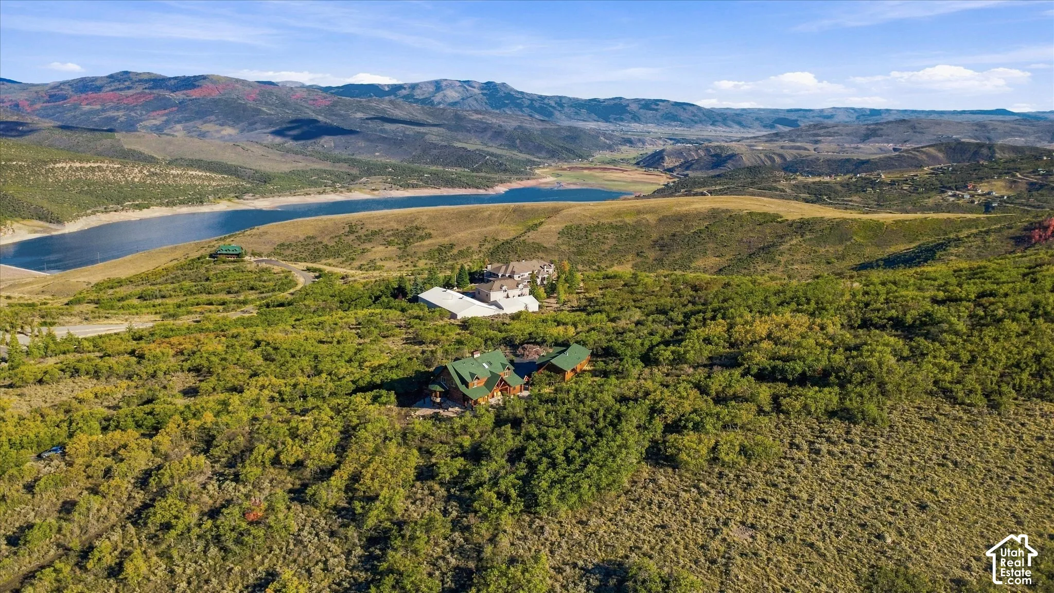 Expansive mountainous landscape featuring a large body of water, distant hills, and verdant natural vegetation