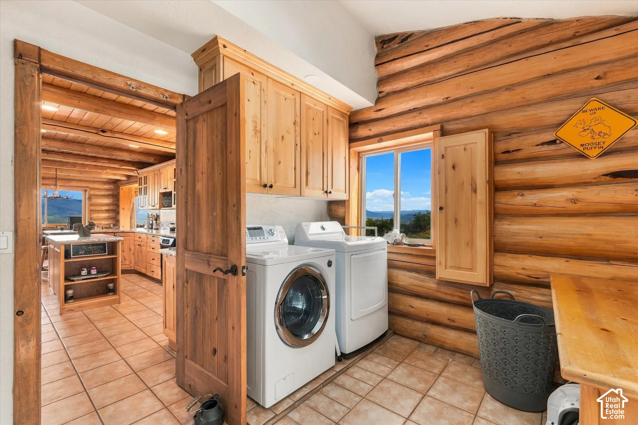Laundry area featuring wood-finish walls, built-in wood-finish cabinetry, tile flooring, and a large window