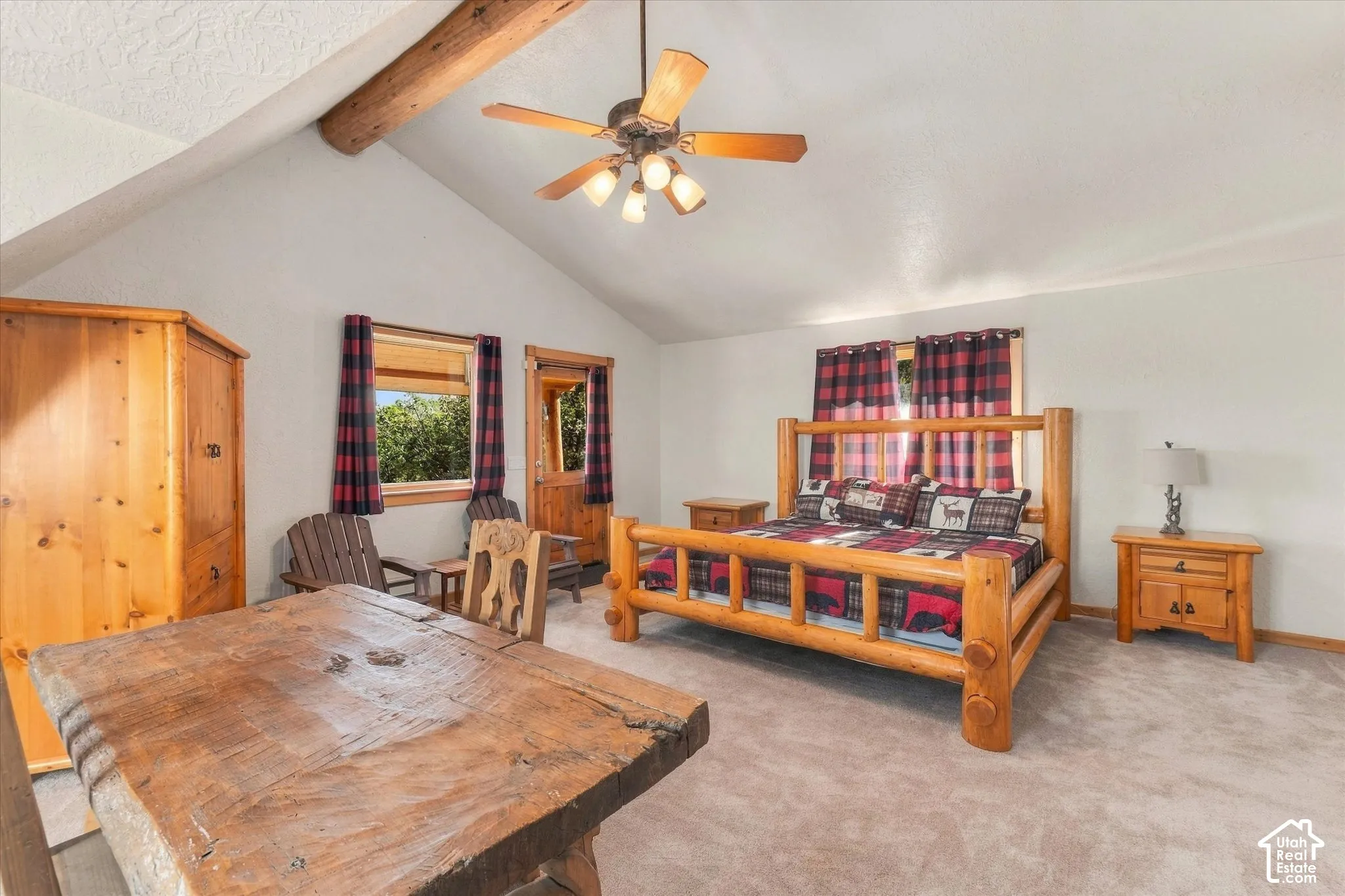 Vaulted ceiling with exposed wood beams, a ceiling fan with integrated lighting, wood-finish flooring, and a solid wood door