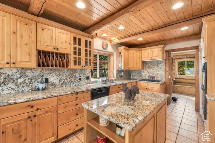 Wood-paneled ceiling with exposed beams, light wood cabinetry, granite countertops, tile flooring, and integrated appliances