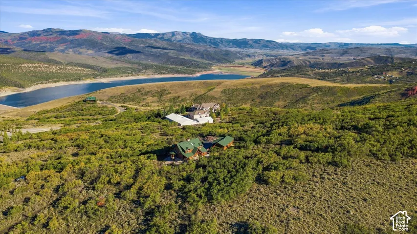 Expansive mountainous landscape featuring a large body of water, distant hills, and verdant natural vegetation