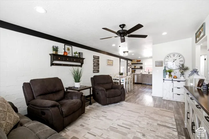 Recessed lighting, ceiling fan, wood-finish flooring, white brick-pattern wall, open-concept design