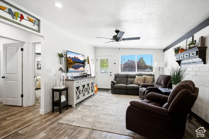 Wood-finish flooring throughout, white interior doors with black hardware, and a ceiling fan with integrated lighting