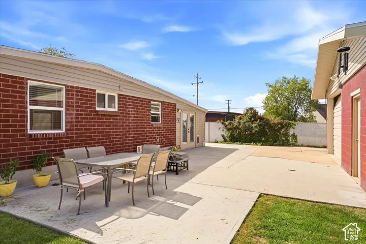 Expansive concrete patio with a brick exterior and a separate building featuring a garage door