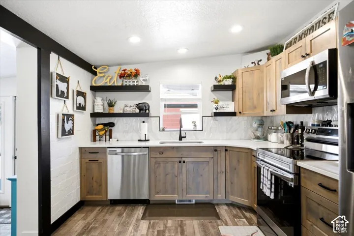 Kitchen featuring wood-finish cabinetry, stainless steel appliances, white countertops, and a tile backsplash