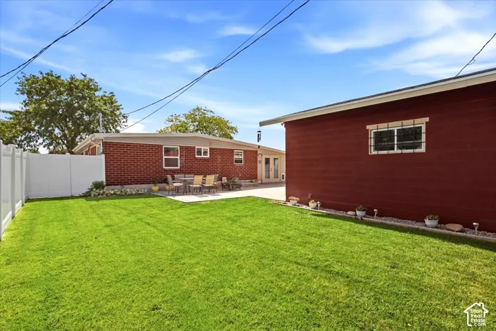 Expansive lawn area with a white privacy fence and a red brick exterior building