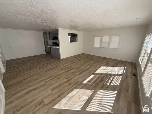 Expansive room with wood-finish flooring, multiple windows, and white painted walls