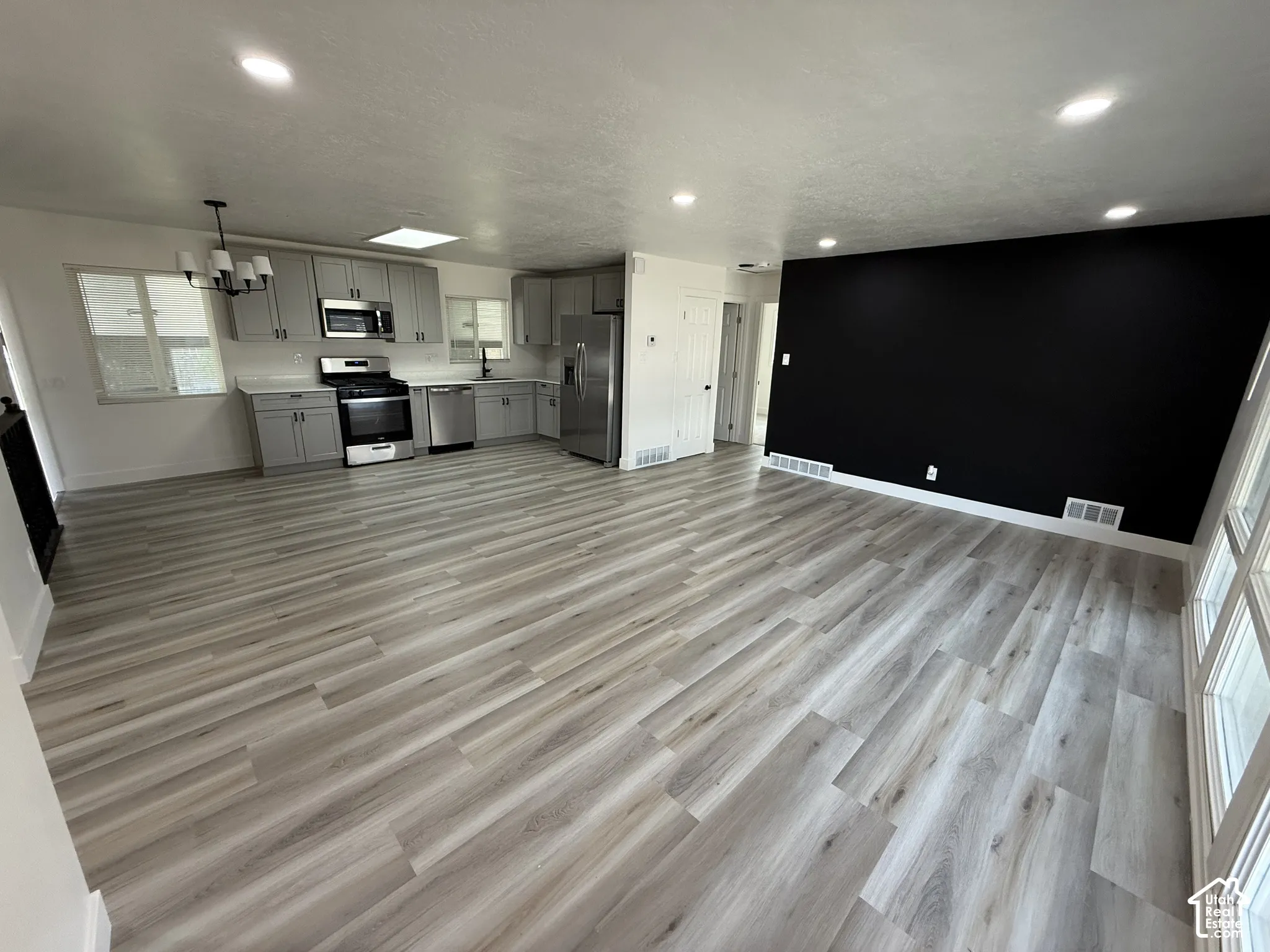 Open-concept living area featuring wood-finish flooring, recessed lighting, and a kitchen with stainless steel appliances