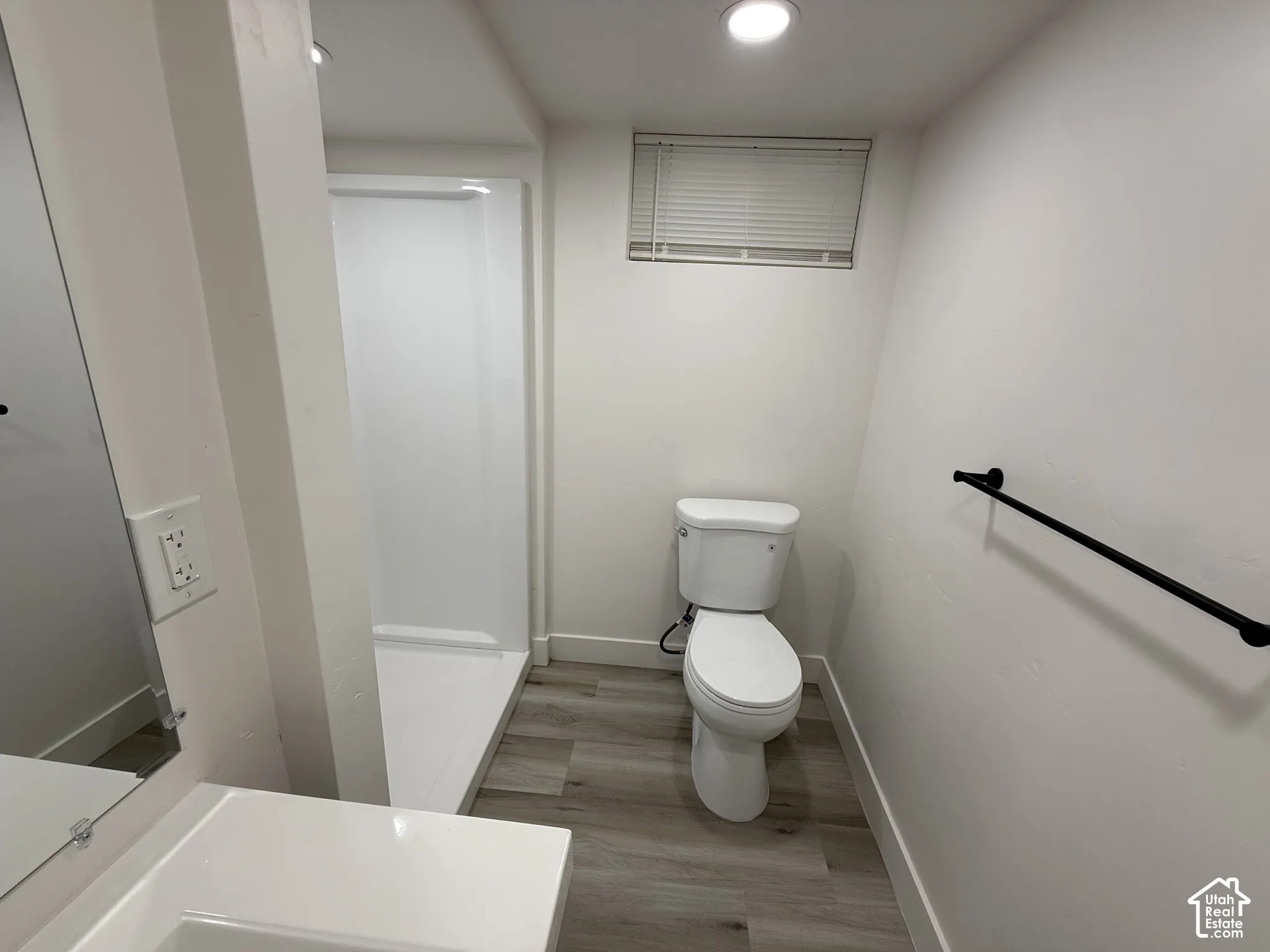 Full bathroom featuring a white toilet, walk-in shower, wood-finish flooring, and recessed lighting
