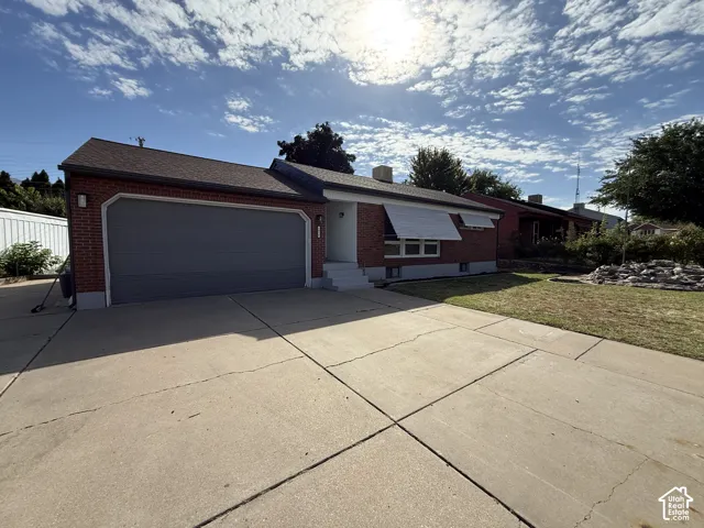 Brick exterior with a dark shingle roof and a concrete driveway