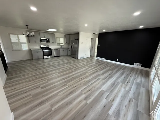 Open-concept living area featuring wood-finish flooring, recessed lighting, and a kitchen with stainless steel appliances