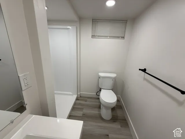 Full bathroom featuring a white toilet, walk-in shower, wood-finish flooring, and recessed lighting