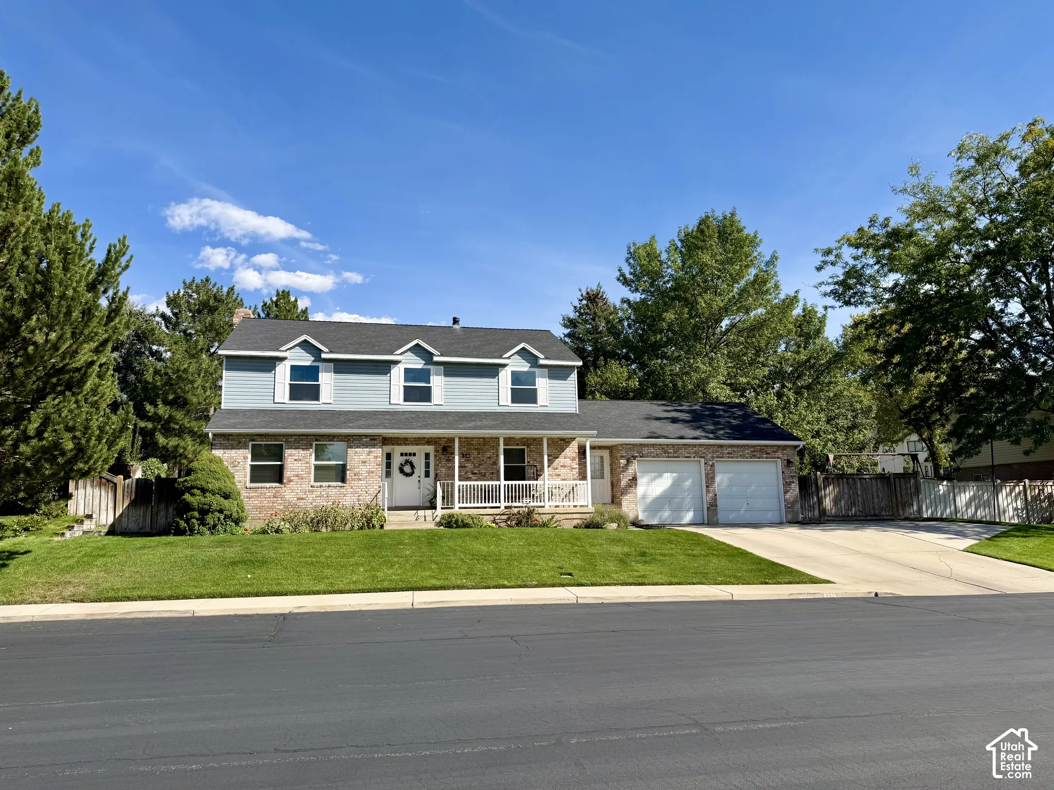 Traditional-style exterior with brick and siding, a covered front porch, and a two-car attached garage