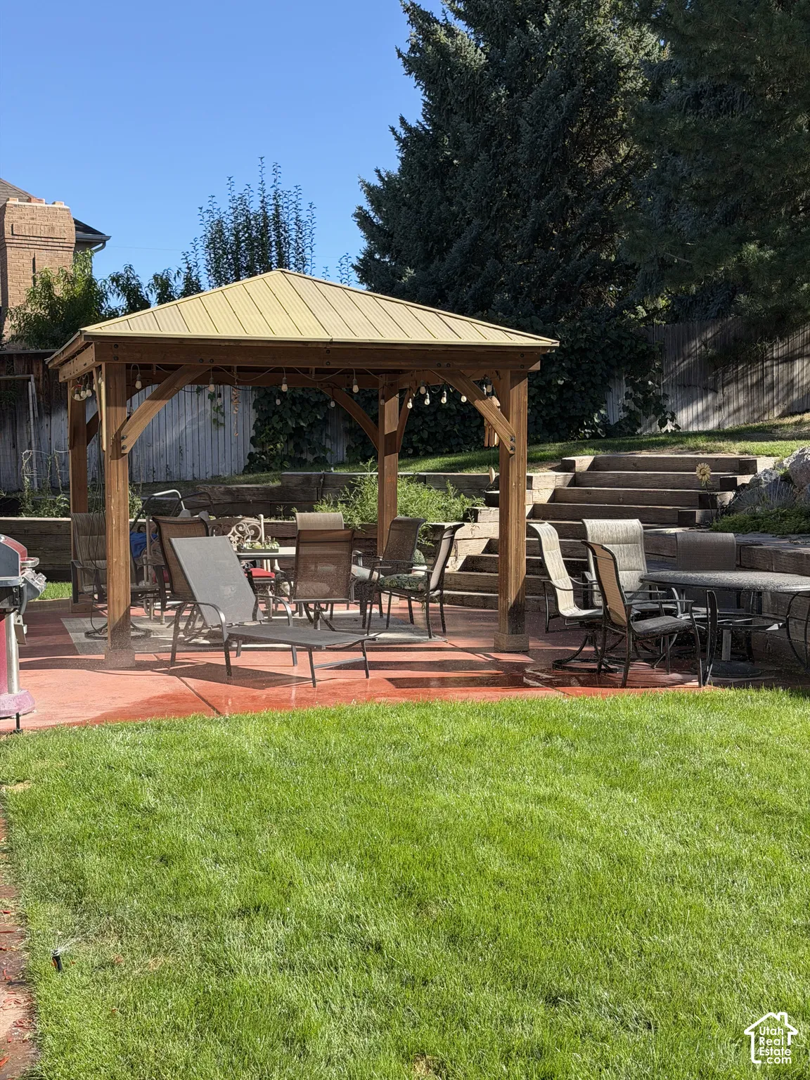 Expansive lawn with a red-toned concrete patio, featuring a wood-frame gazebo