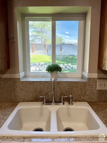 Dual basin sink with a chrome faucet, with a window overlooking a fenced yard