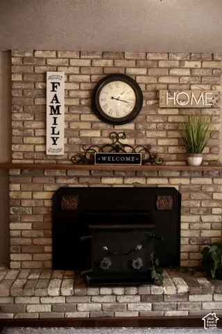 Brick fireplace featuring a hearth, mantel shelf, and a black wood-burning stove insert