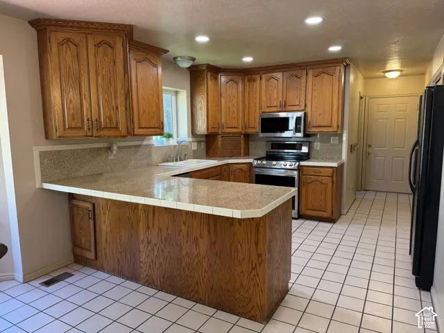 Wood-finish cabinetry, light-toned countertops, and tiled floor