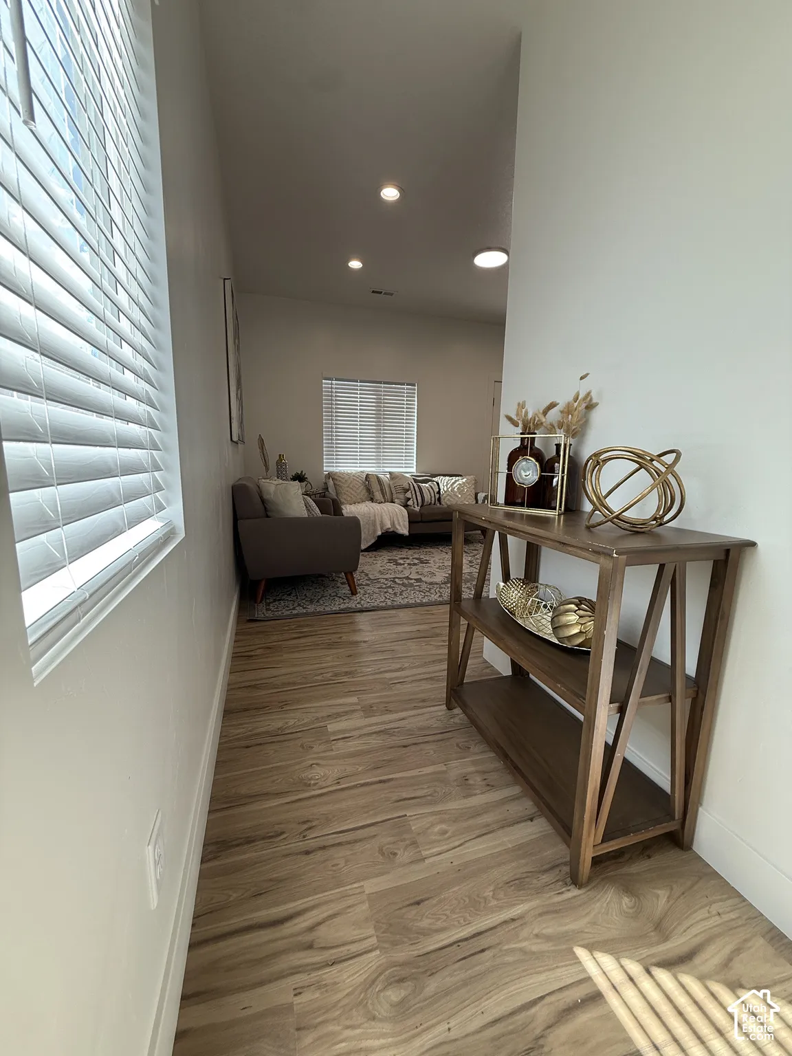 Wood-finish flooring throughout, recessed lighting, and a window with blinds provide natural illumination