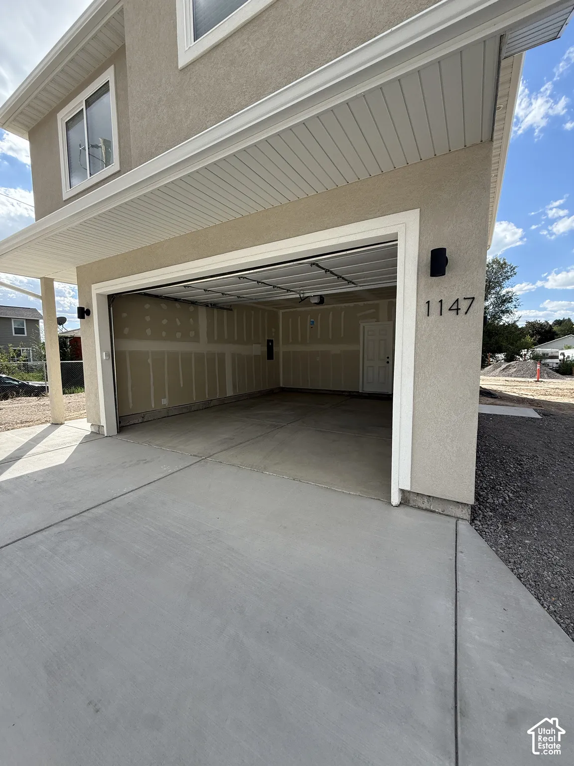 Integrated two-car garage, stucco exterior, concrete driveway, and exterior lighting fixtures