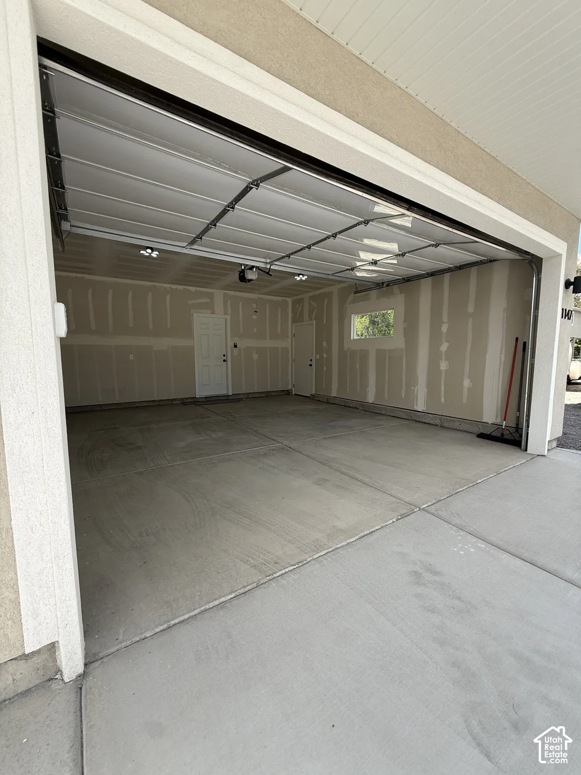 Spacious garage featuring a concrete floor, overhead lighting, and an automatic garage door opener