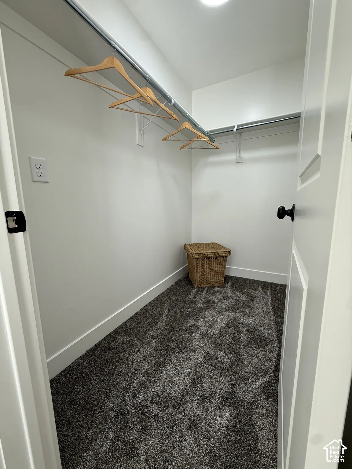 White painted walls, gray plush carpeting, recessed ceiling lighting, and a metal hanging rod with shelving