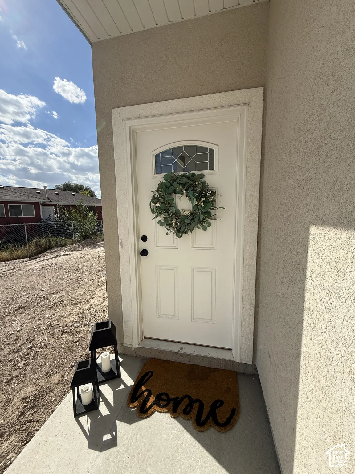 White entry door with decorative glass panel, black hardware, and stucco exterior