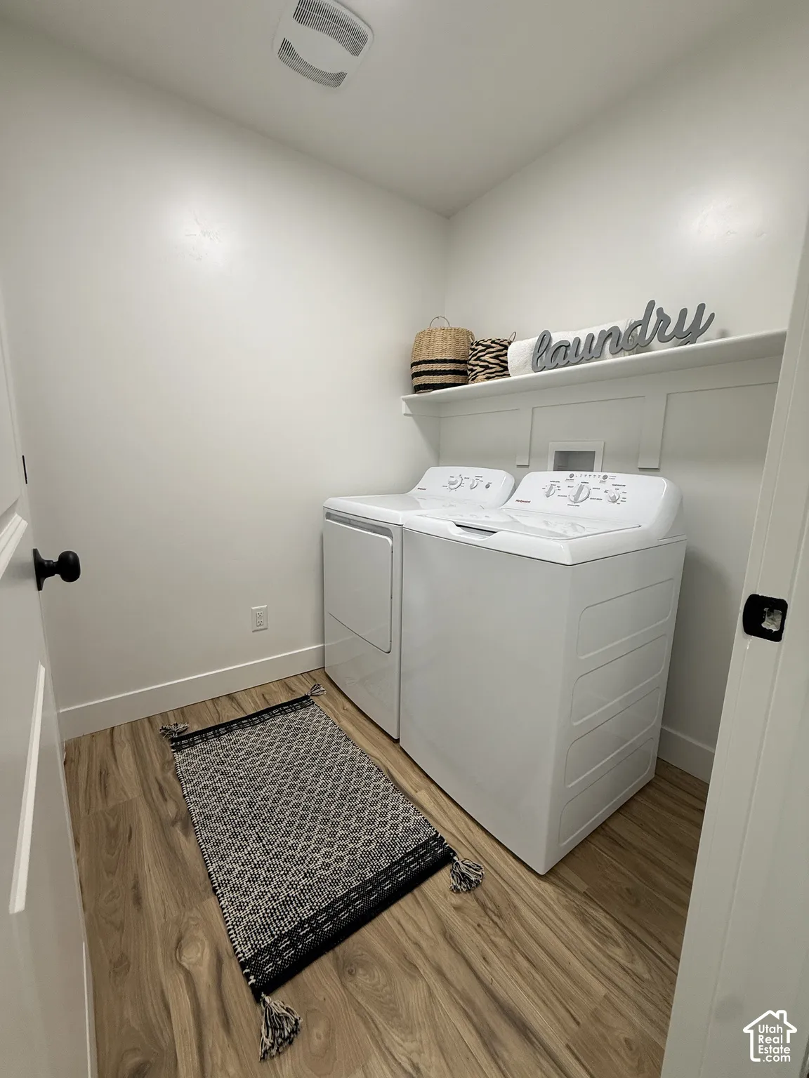 Wood-finish flooring, overhead ceiling light fixture, white walls, and built-in shelving