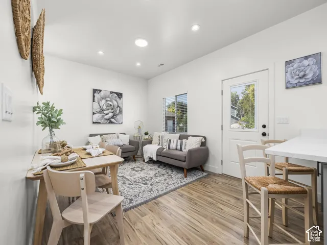 Open-concept living area featuring wood-finish flooring, recessed lighting, and a white paneled door with window insert