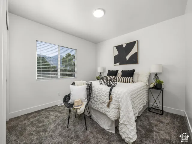 Recessed lighting illuminating the room, textured gray carpet, and a window featuring horizontal blinds