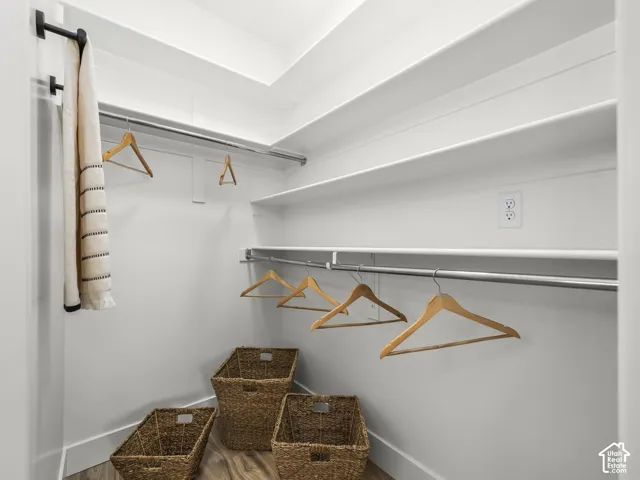 White shelving, chrome hanging rods, and wood-finish flooring