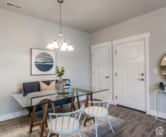 Wood-finish flooring with a decorative area rug, white interior doors with dark hardware, and a glass-top table with a wood base
