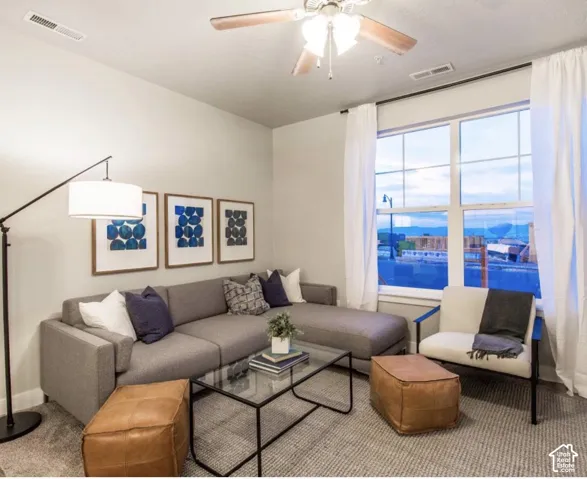 Spacious living area featuring large windows, a ceiling fan, and light-toned walls
