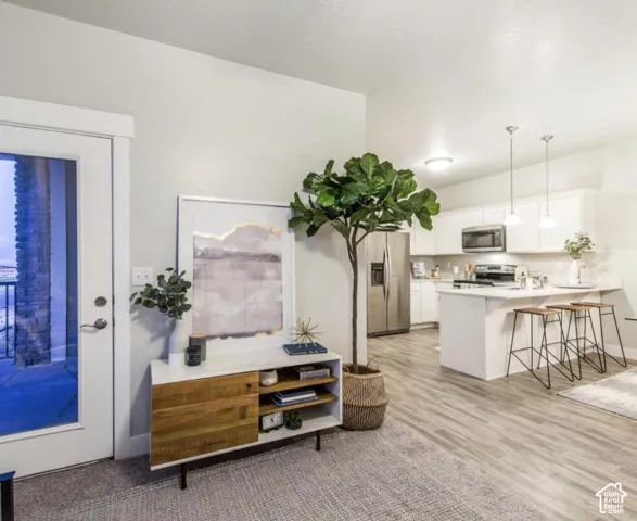 White kitchen cabinetry with stainless steel appliances, central kitchen island with seating, and pendant lighting