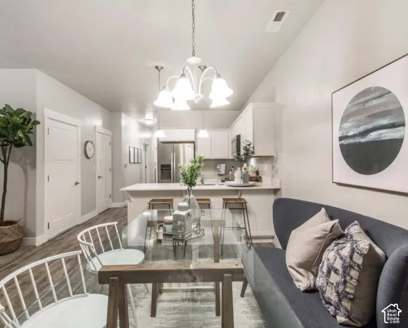 Open-concept living space with wood-finish flooring, white cabinetry, a kitchen island, and stainless steel appliances
