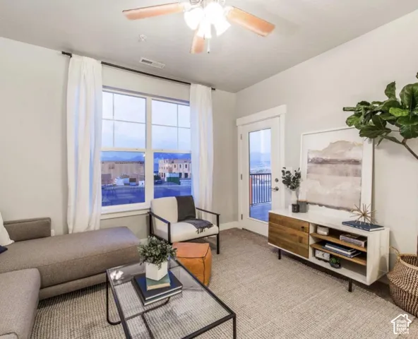 Recessed lighting, wood-finish ceiling fan, large window with white drapery, glass-paneled door, and built-in media console