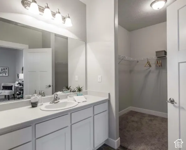 White vanity with built-in cabinetry, an integrated sink, and an expansive mirror
