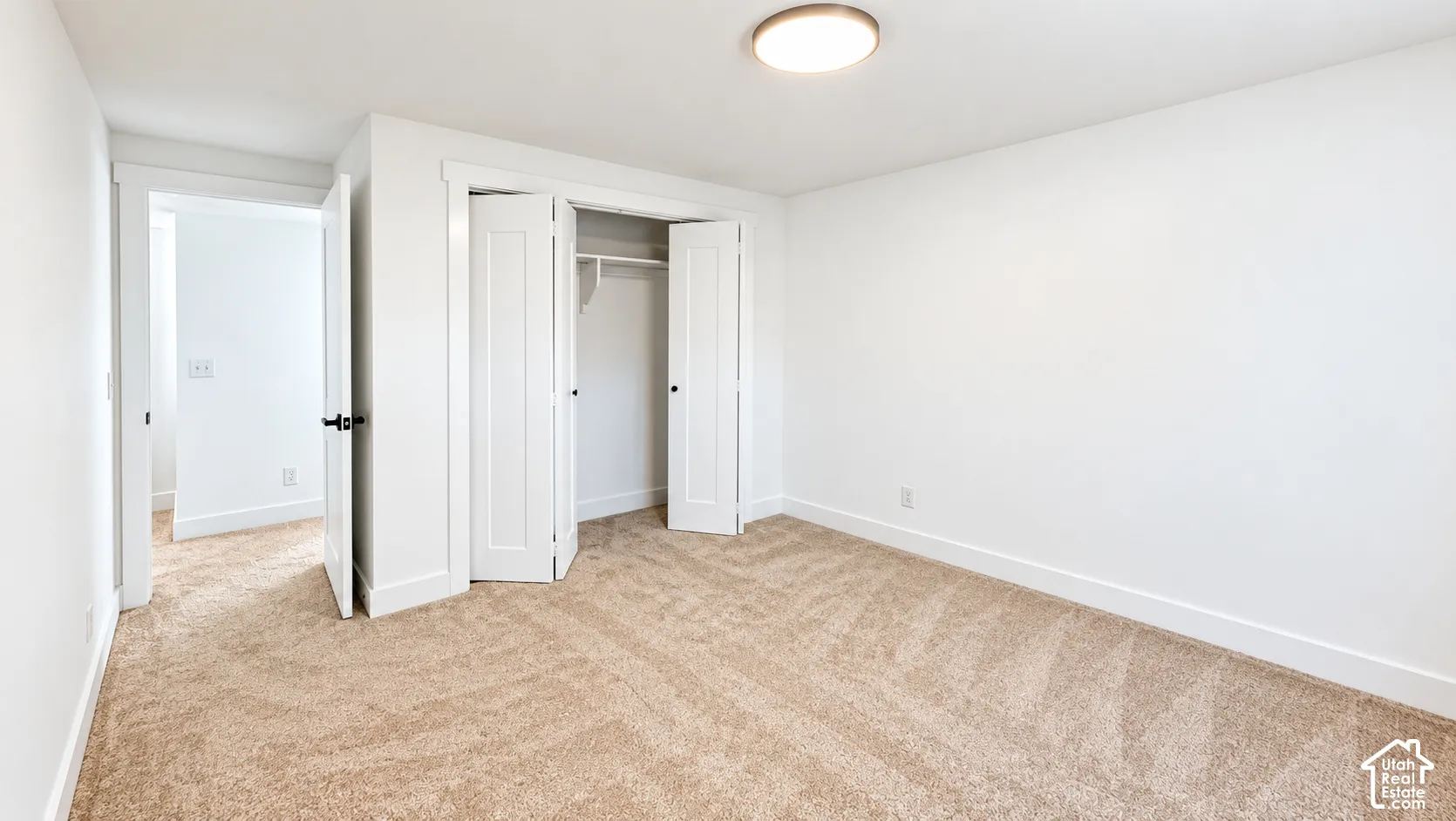 Wall-to-wall carpet flooring, white walls, flush mount lighting, and built-in closet with bifold doors