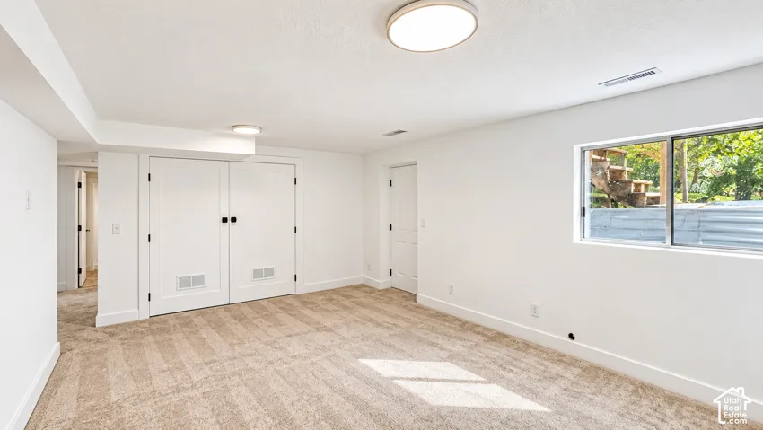 Light-colored carpeting, white walls, and a window with a wood-framed exterior structure