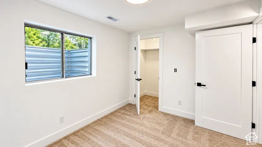 White walls with clean trim, a window with an egress well, and a closet with a solid door