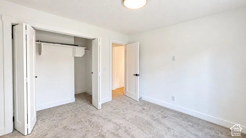 Light-toned carpeting and white walls with a built-in closet featuring bi-fold doors