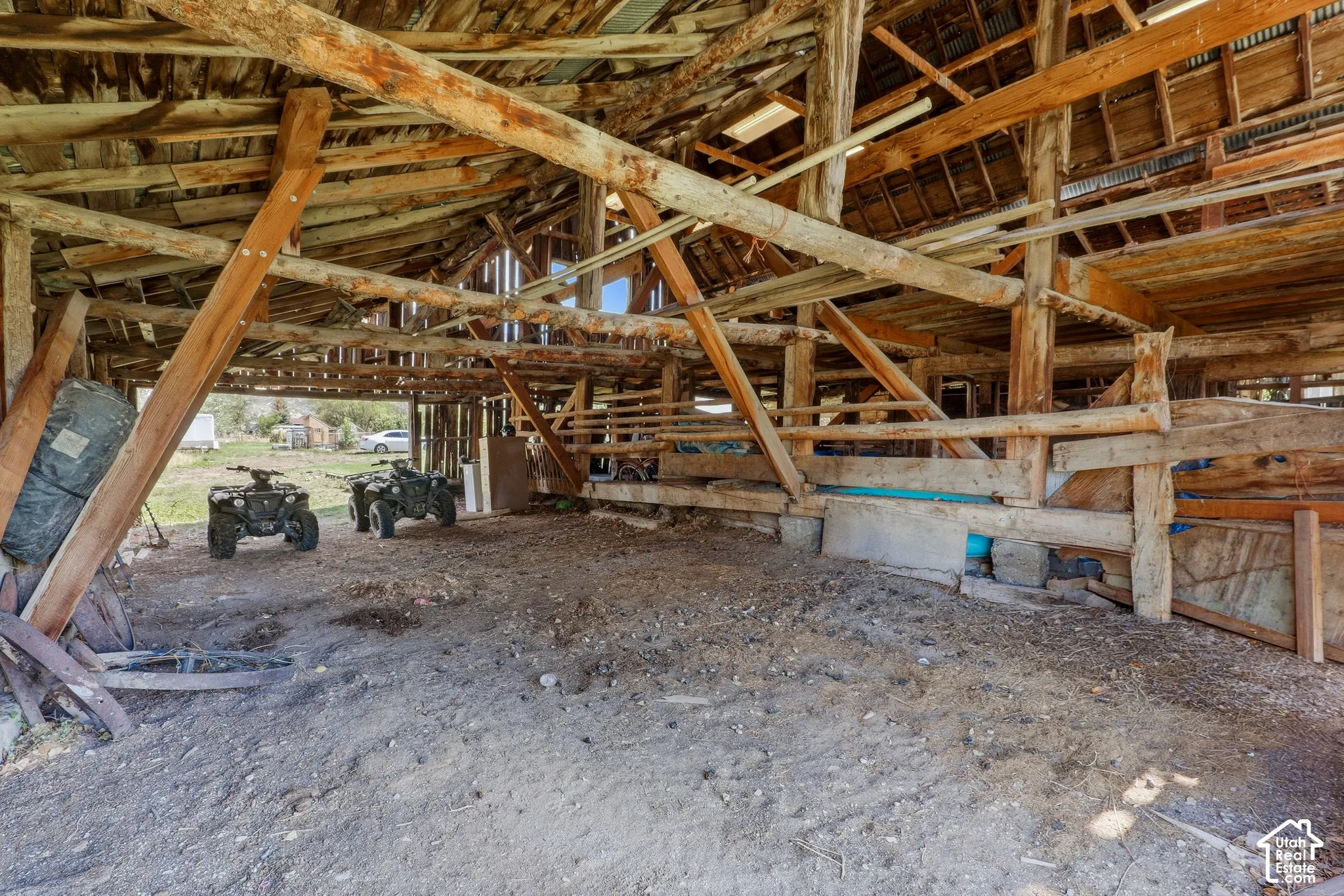 Exposed wood beam construction with a corrugated metal roof and dirt flooring
